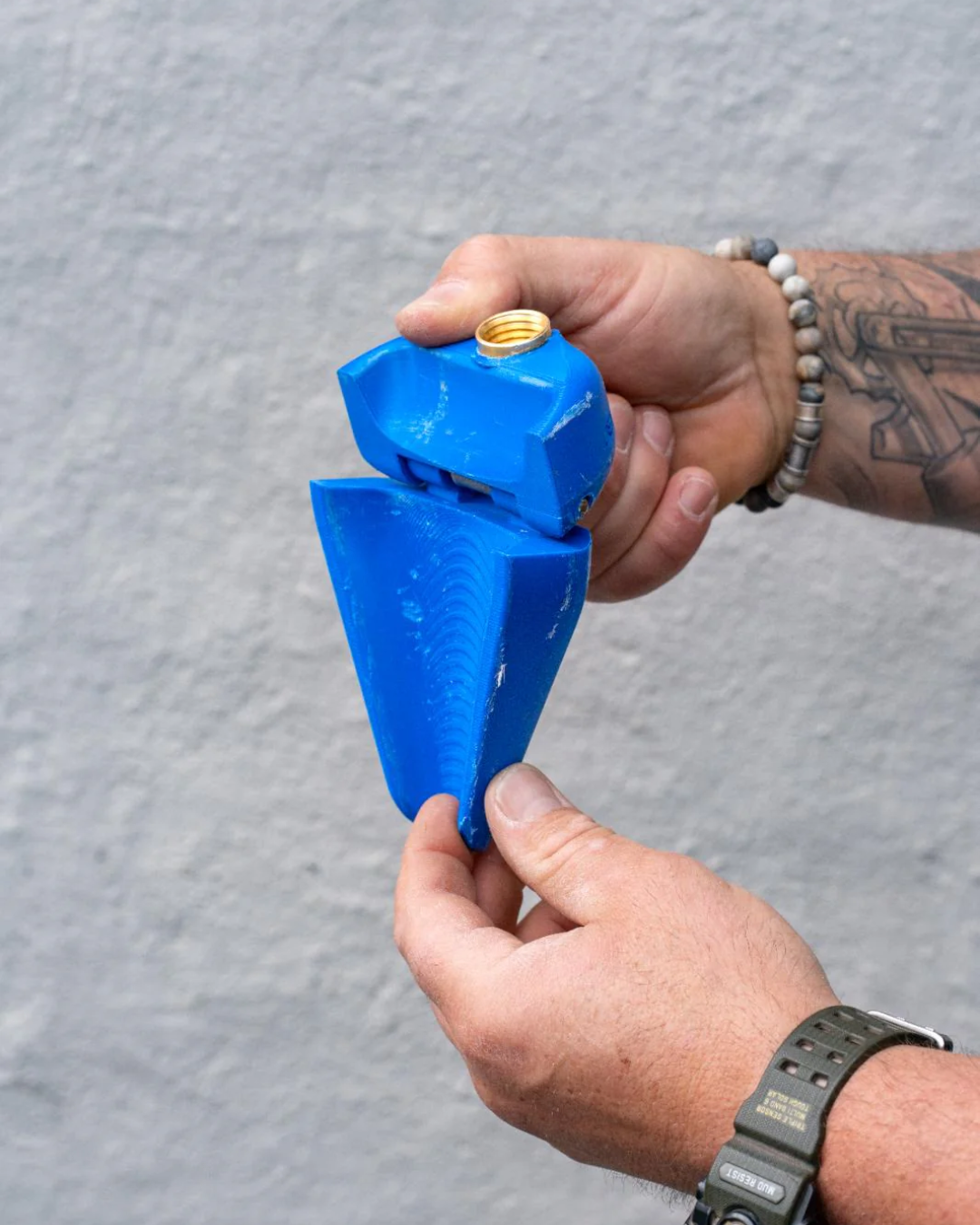 Person holding a blue jet mate tool against a gray background
